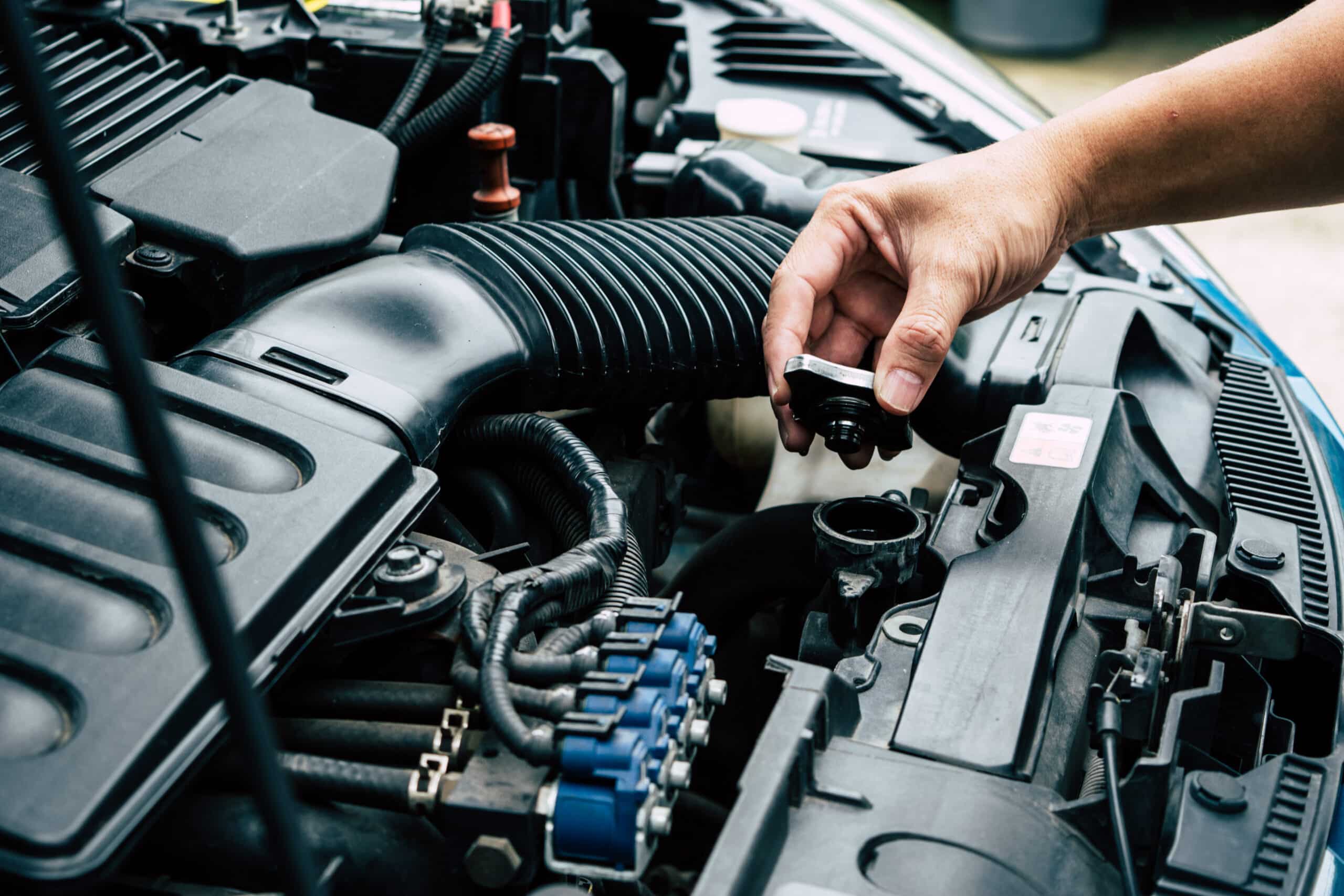 Hand holding a radiator cap above the radiator filler neck